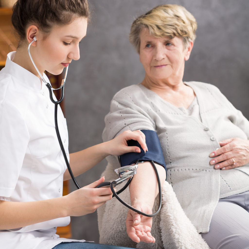 nurse taking elderly womans blood pressure PYWURTK